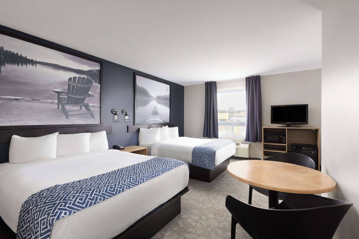 Une chambre d’hôtel avec deux lits, un bureau, une télévision et une vue sur un lac.