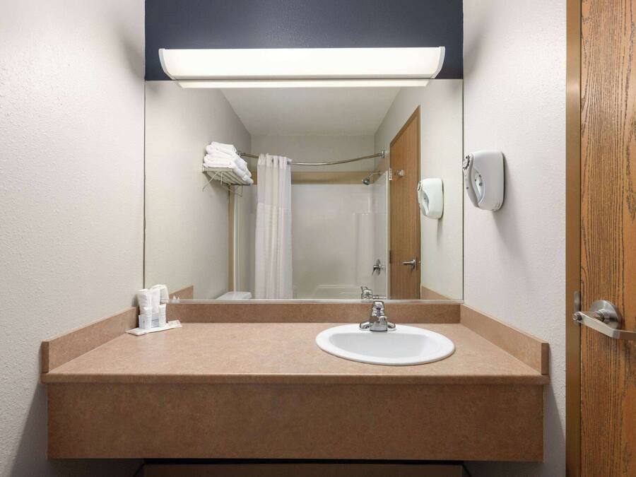 Un baño con lavamanos, espejo, toallero y cortina de ducha.