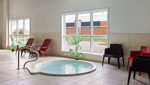 Zona de piscina interior con sillas y vistas a un edificio cercano.