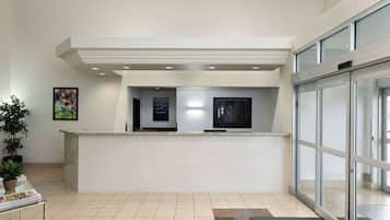 A reception area with a counter, a television, and a glass door.