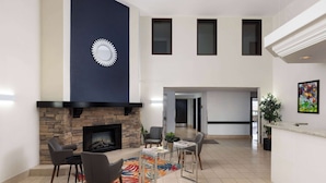 Amplia sala de estar con chimenea de piedra, asientos modernos y un reloj grande en la pared.