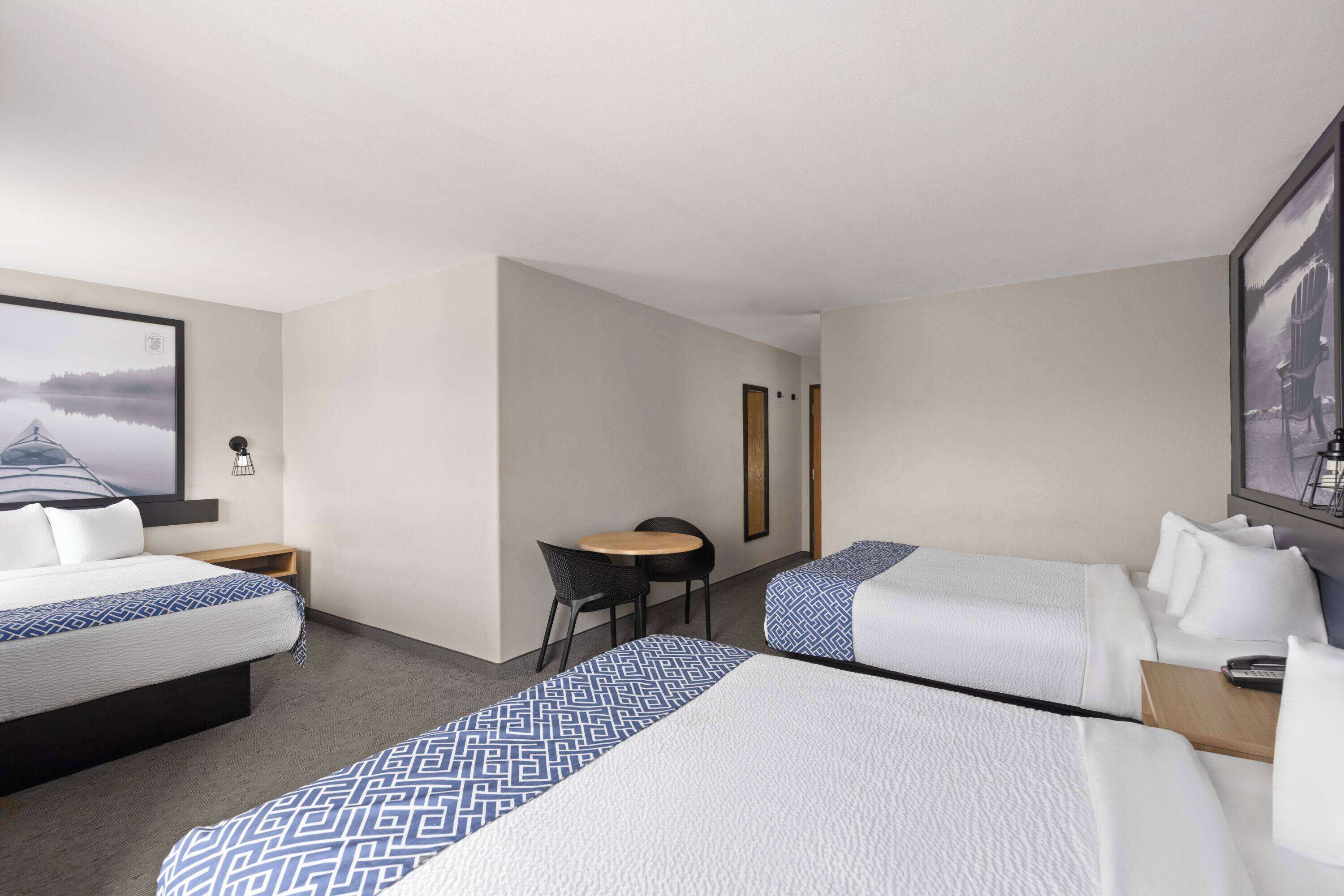 Une chambre d’hôtel avec deux lits, un bureau et une chaise.