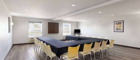 A conference room with a long table, chairs, and a television.