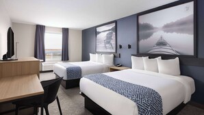 Habitación de hotel con dos camas, un escritorio, una silla y cuadros grandes enmarcados en las paredes.