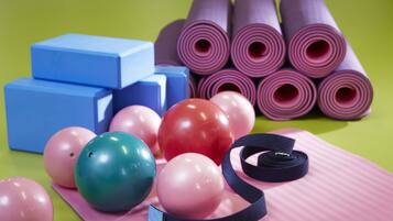 A collection of exercise equipment including yoga mats, foam blocks, and exercise balls on a green surface.