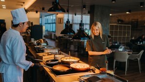 Een kok bereidt eten in een moderne keuken met hangende吊灯 en verschillende kookgerei en ingrediënten op het aanrecht.