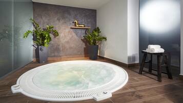 A spa room with a hot tub, two potted plants, a gold horse sculpture, and a towel stand.