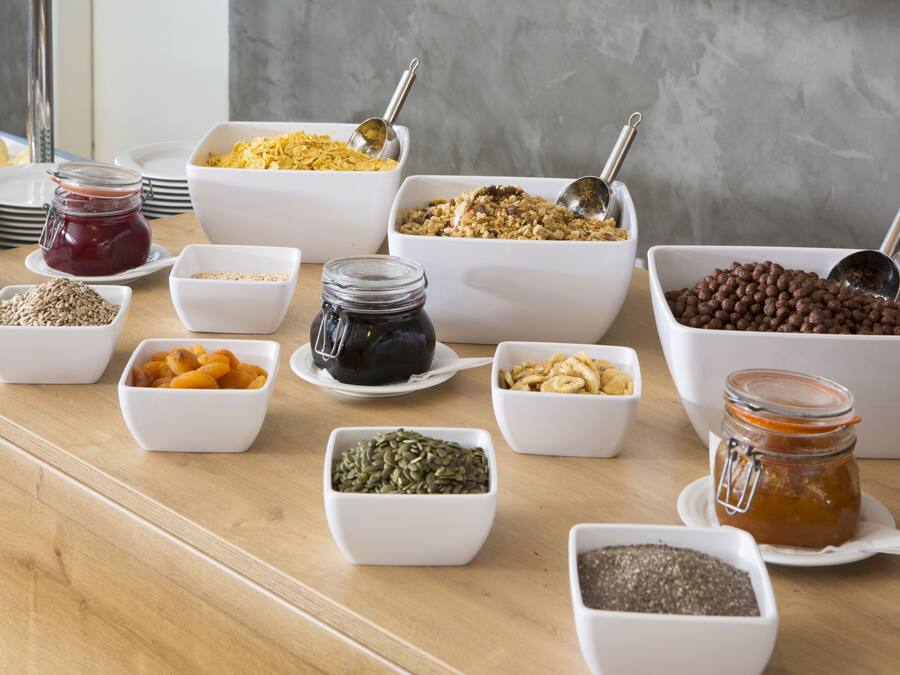 A buffet table with various food items and condiments in white bowls and jars.