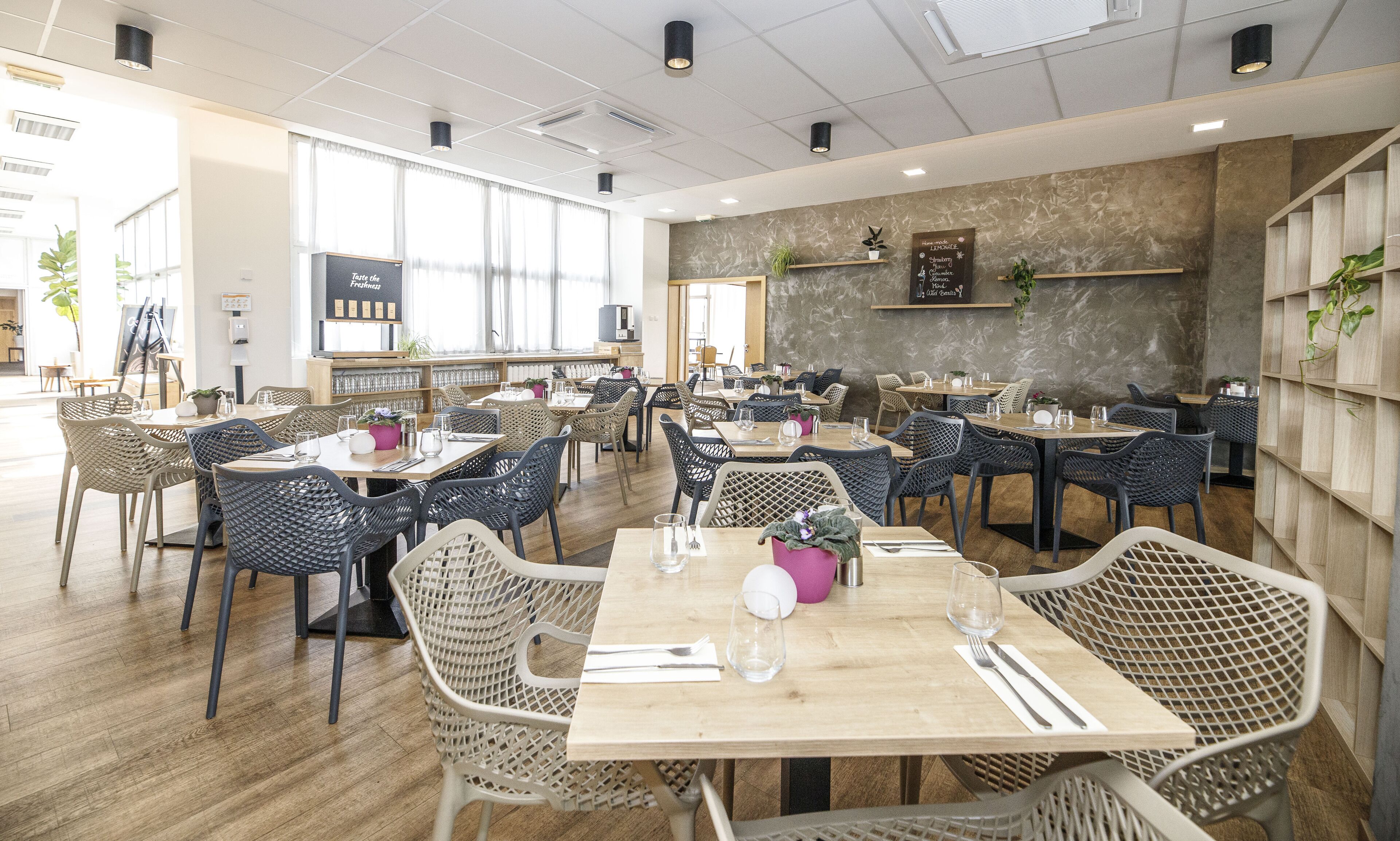 Un restaurant spacieux, doté de nombreuses tables et chaises, de grandes fenêtres et d’un aménagement intérieur moderne.