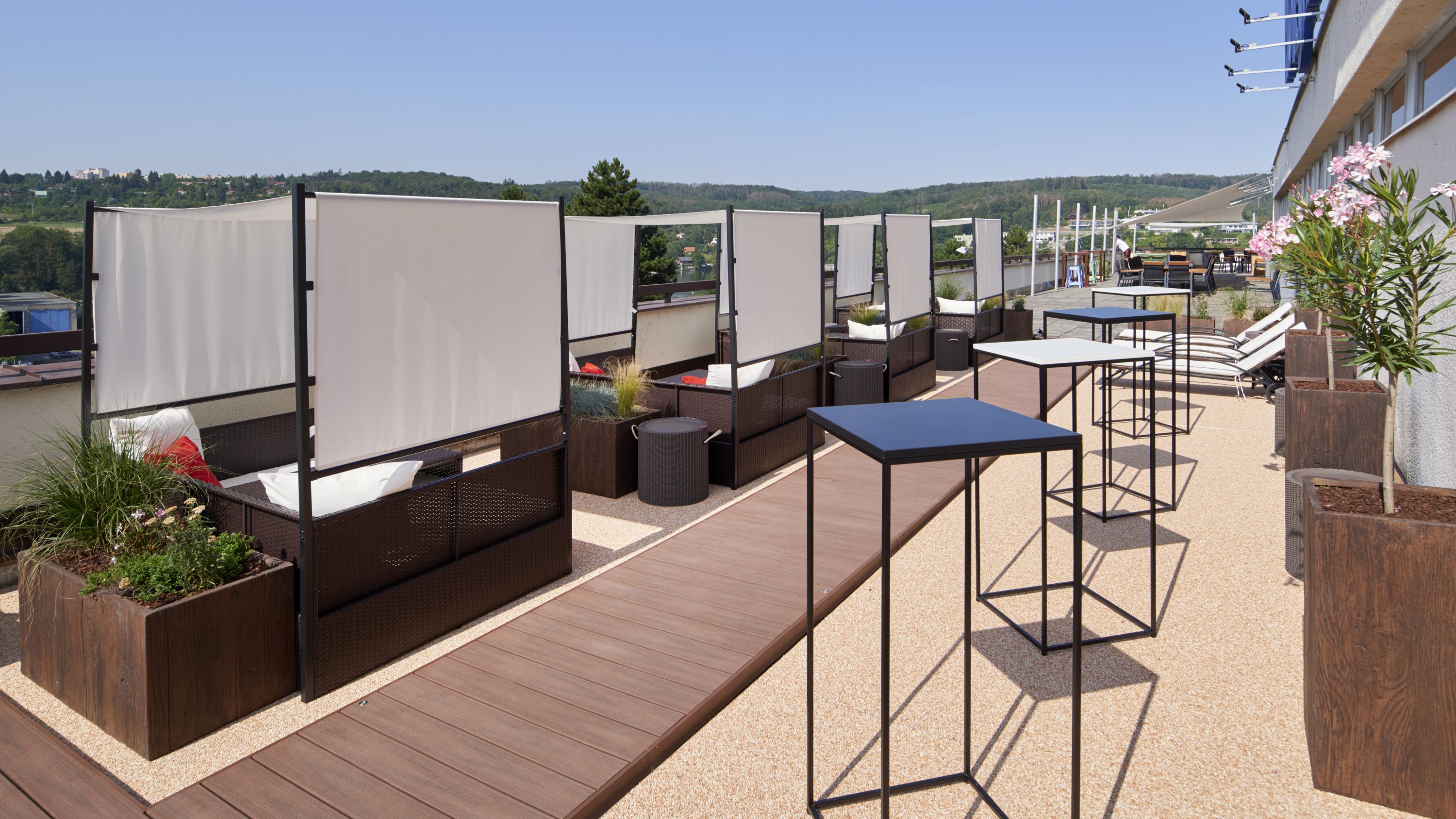 An outdoor seating area with wooden deck, cushioned seating, and tables.