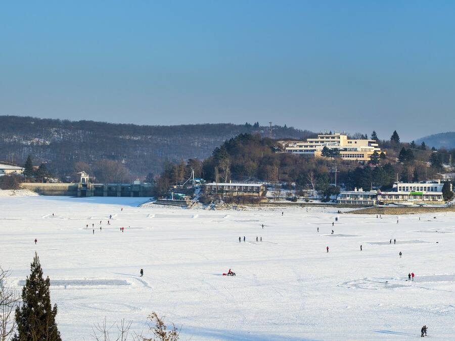 Een groot, open gebied met meerdere gebouwen op de achtergrond, vermoedelijk een wintersportgebied met een vlak, besneeuwd terrein.