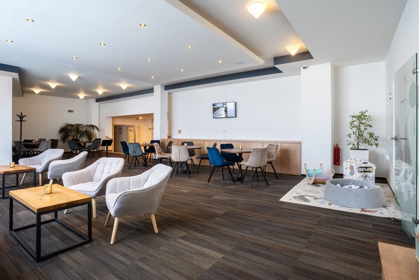 Un espacio lounge moderno con diversas opciones de asientos, incluyendo sofás y sillones, dispuestos alrededor de mesas.