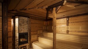 A log cabin interior with a fireplace, wooden walls, and a bench. - Orea Resort Santon Brno (Brno)