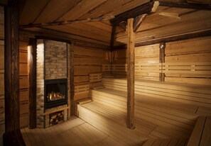 A log cabin interior with a fireplace, wooden walls, and a bench. - Orea Resort Santon Brno (Brno)