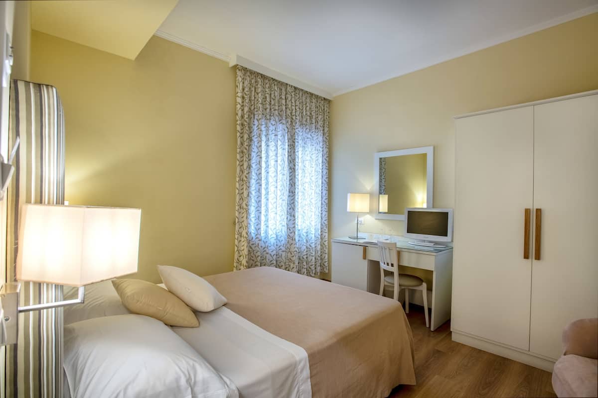 Een hotelkamer met een bed, bureau, stoel en kast.