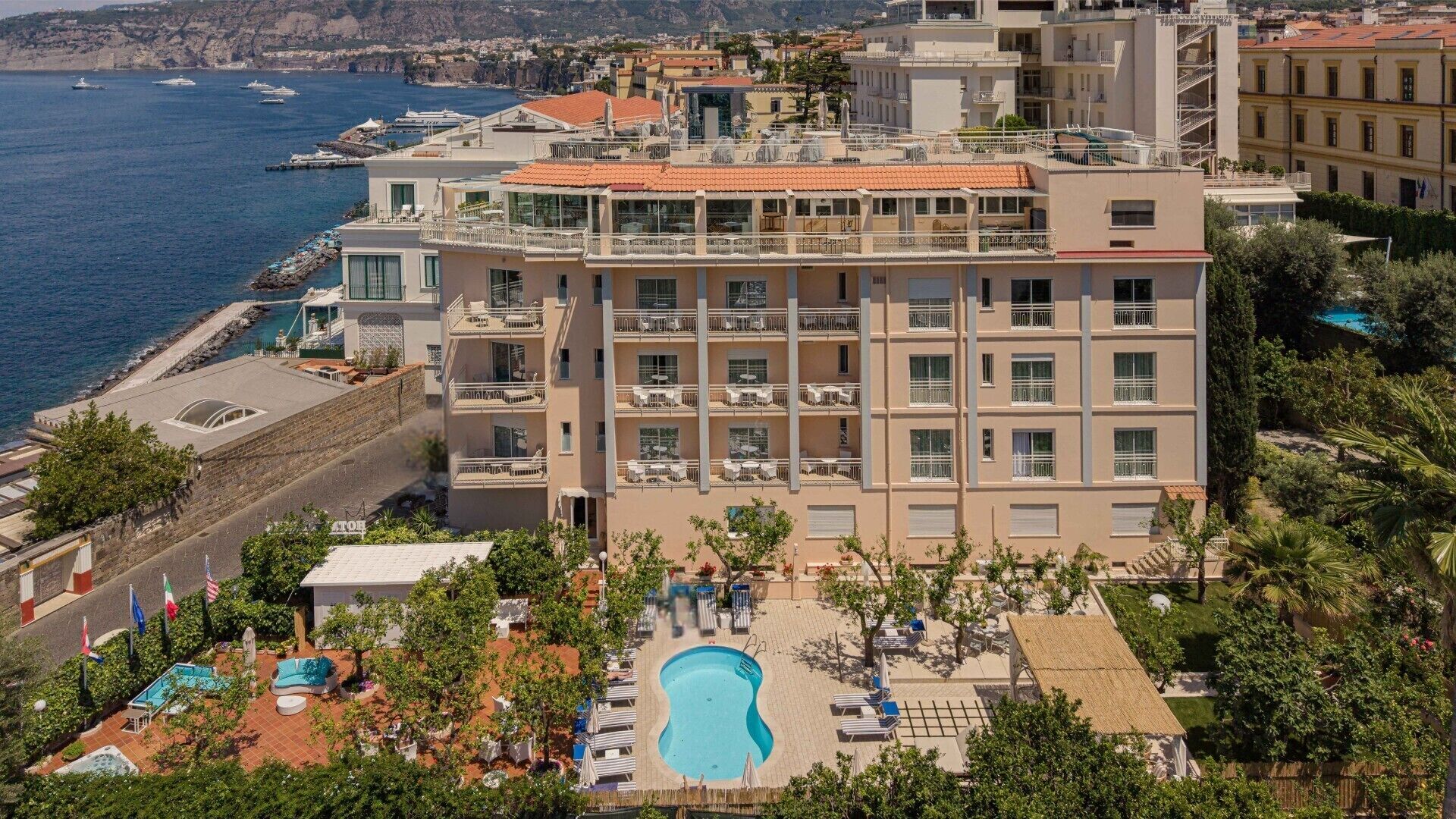 Un hotel con piscina, diversi balconi e vista sul mare.