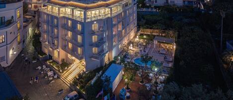 A multi-story hotel with balconies, a swimming pool, and outdoor seating areas.