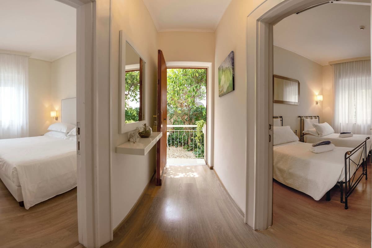 Een hotelkamer met twee bedden, een balkon en uitzicht op groen.