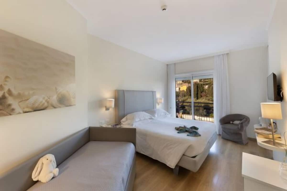 Een hotelkamer met een bed, een bank, een stoel, een bureau, een lamp en een schilderij aan de muur.