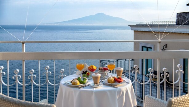 Ein Balkon mit einem Tisch, Frühstücksgebäck und Blick aufs Meer.