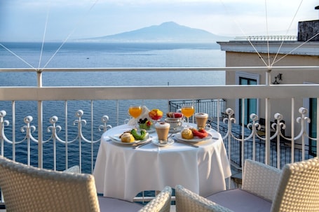 A balcony table with breakfast items and a view of the sea.. Hotel Regina Sorrento