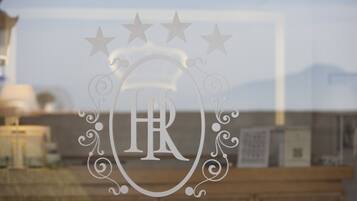 Une fenêtre ornée d’un motif décoratif représentant les lettres « HR » et des étoiles, avec un arrière-plan flou de bâtiments.