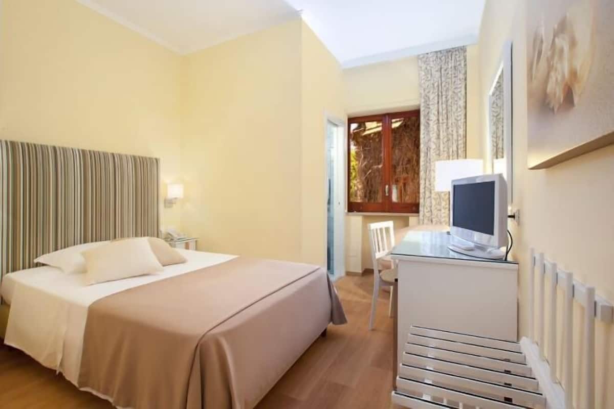 Een hotelkamer met een bed, bureau, stoel en televisie.