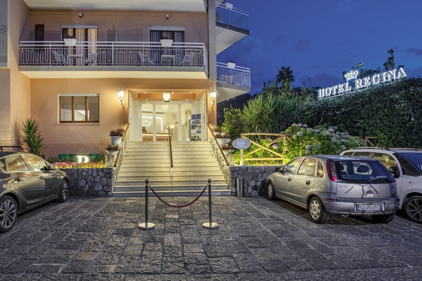 A hotel entrance with a staircase, a reception desk, and a sign reading 'HOTEL REGINA.'