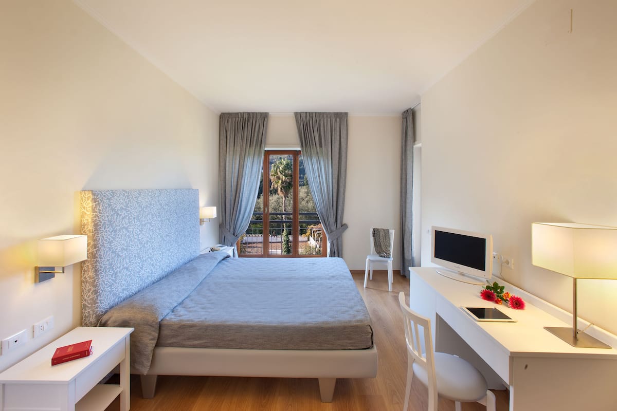 Een moderne hotelkamer met een bed, bureau en televisie.