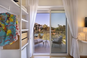 A balcony with a chair and table, a view of buildings, and a TV on the wall. - Hotel Regina Sorrento (Sorrento)
