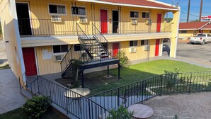 A two-story motel with a red door, a balcony, and a small outdoor seating area. - Ladybird Inn (Johnson City)