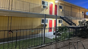 A multi-story building with a yellow facade, red doors, and a black metal fence. - Ladybird Inn (Johnson City)