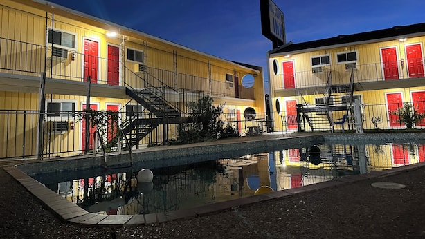A yellow building with red doors and a small pool in front. - Ladybird Inn (Johnson City)