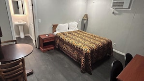 A bedroom with a bed, bedside table, lamp, and a small table with chairs. - Ladybird Inn (Johnson City)