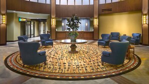 A spacious lobby with a high ceiling, a central chandelier, multiple seating areas, and a reception desk.