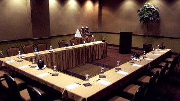 Un salón de conferencias con una larga mesa, sillas y un atril.