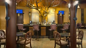 A bar area with wooden chairs, a bar counter, and hanging pendant lights.