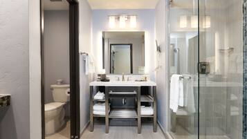 A modern bathroom with a glass shower enclosure, a white sink with a vanity, and a toilet.