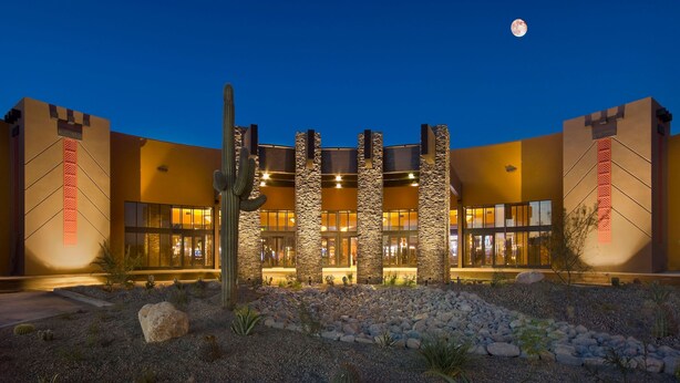 A hotel with a desert garden, stone pillars, and a night sky with a moon.