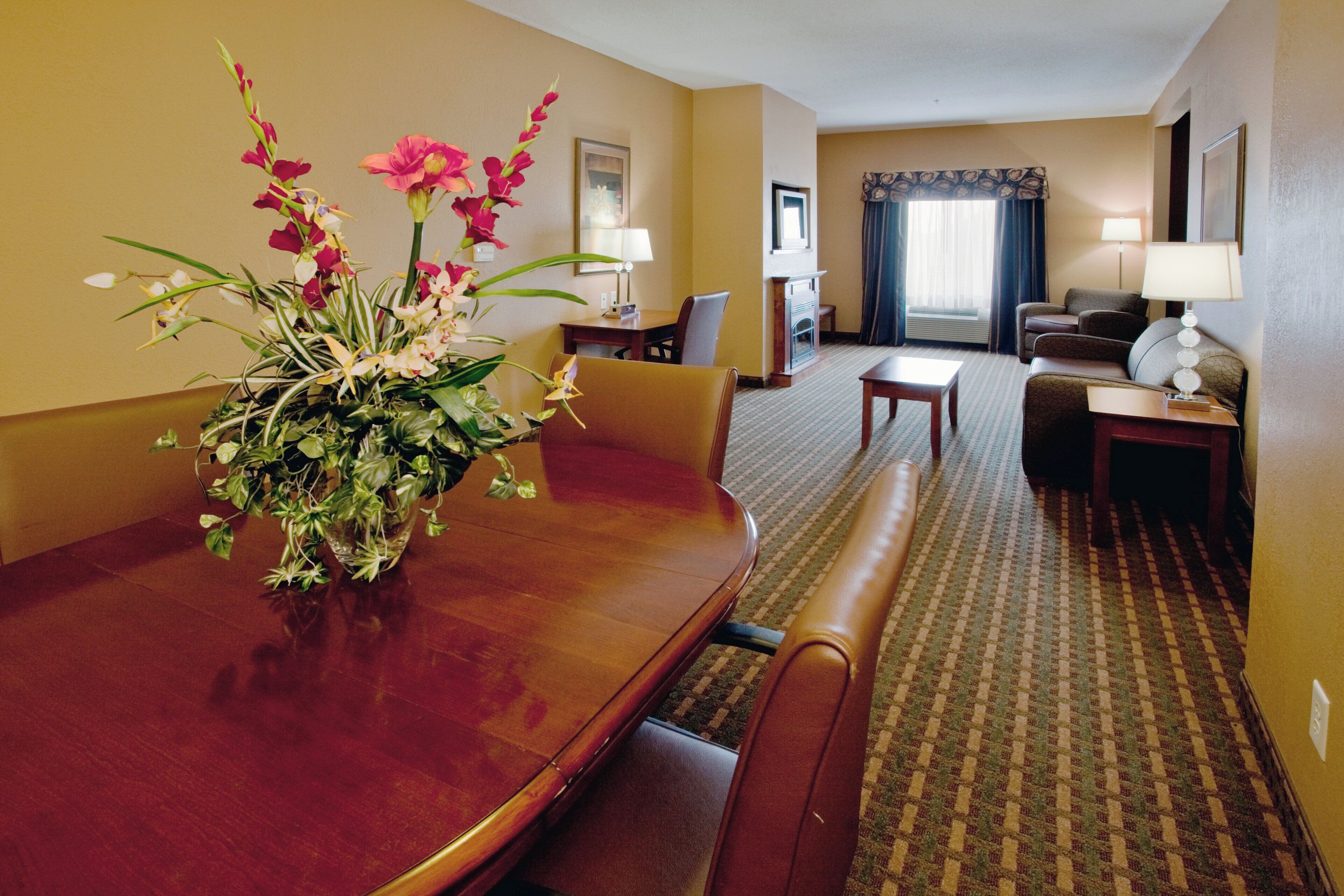 Una habitación de hotel con una mesa de comedor, sillas, un sofá, una mesita y una lámpara.