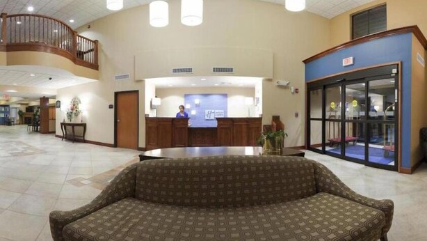 A spacious lobby with a reception desk, a staircase, and a glass door entrance.