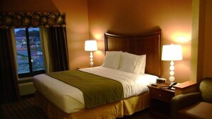 A hotel room with a large bed, two bedside lamps, a chair, and a desk.