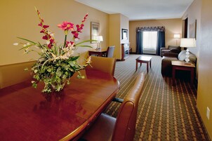 Habitación de hotel con una mesa de comedor, sillas, un sofá, un televisor y una chimenea.
