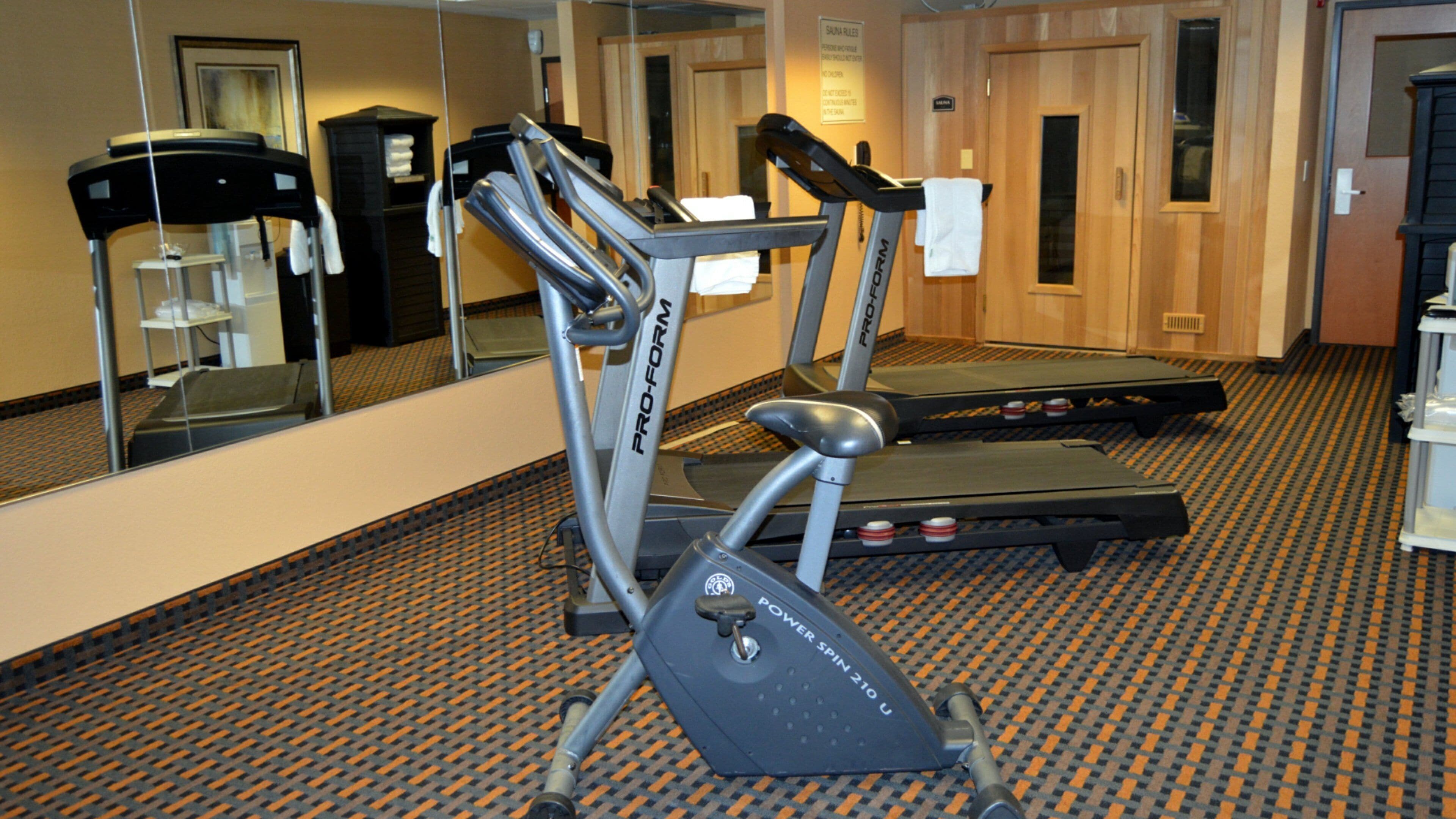 A gym with treadmills and a mirrored wall.