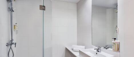 A modern bathroom with a glass-enclosed shower, a white sink, and a large mirror.