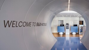 A modern hotel lobby with a curved wall displaying "WELCOME TO B&B HOTELS" and reception counters. - B&B Madrid Aeropuerto T1 T2 T3 (Madrid)
