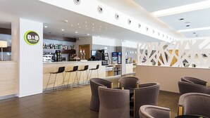 A modern hotel lobby with a reception desk, bar area, and seating arrangement. - B&B Madrid Aeropuerto T1 T2 T3 (Madrid)