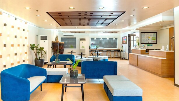 A modern hotel lobby with blue sofas, a reception desk, and a dining area. - Microtel by Wyndham Davao (Davao)
