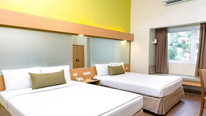 A hotel room with two beds, a mirror, a bedside table with a phone, and a window with curtains. - Microtel by Wyndham Davao (Davao)