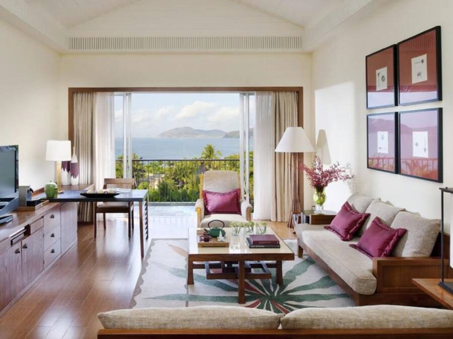 A spacious living room with a large TV, a sofa, a coffee table, and a dining area with a view of the ocean.